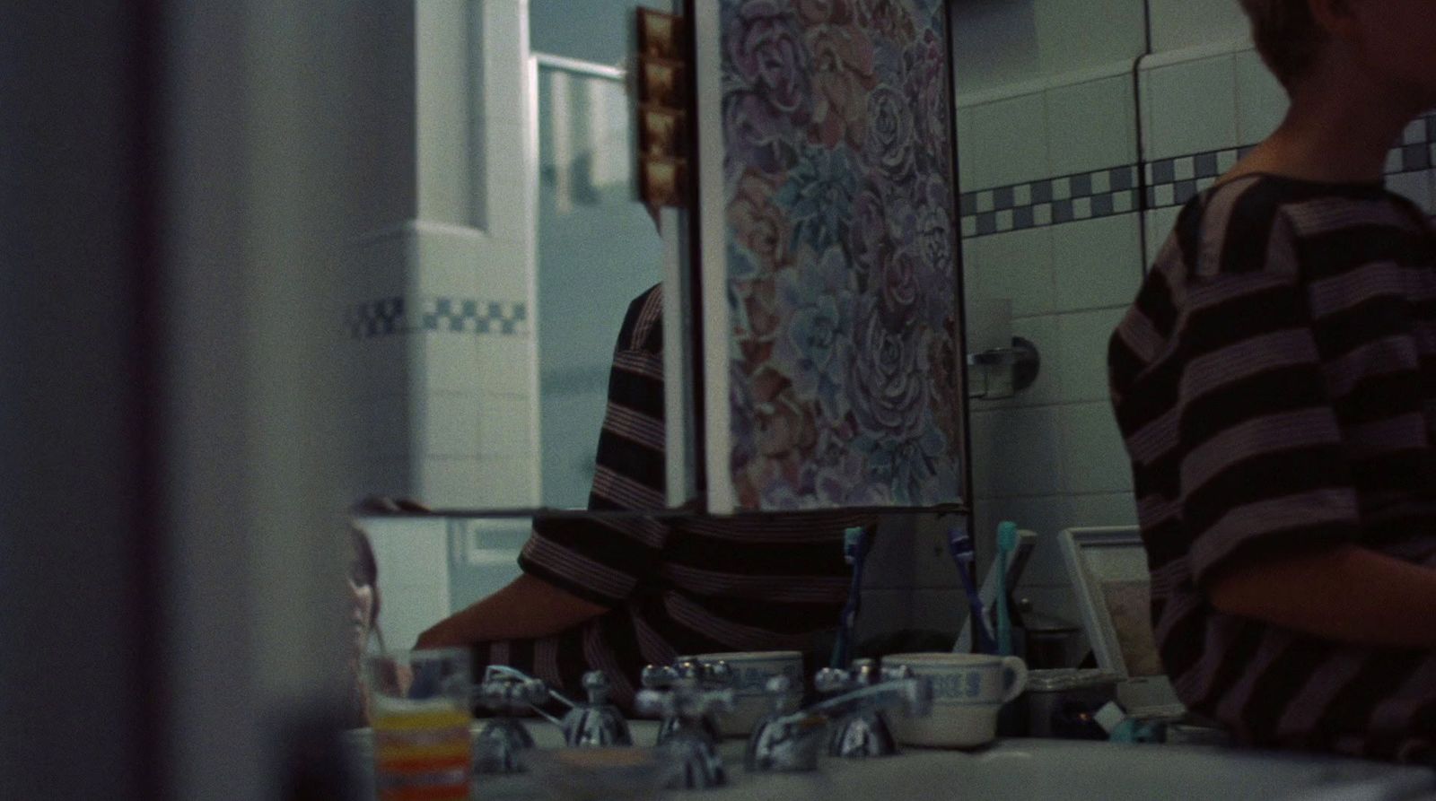 a young boy standing in front of a bathroom mirror