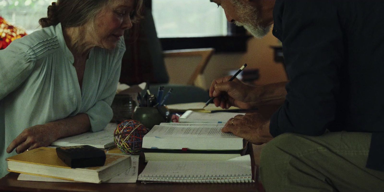 a man and a woman sitting at a table with books