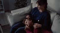 a woman sitting next to a child on a couch