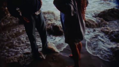 a couple of people standing on a beach next to the ocean