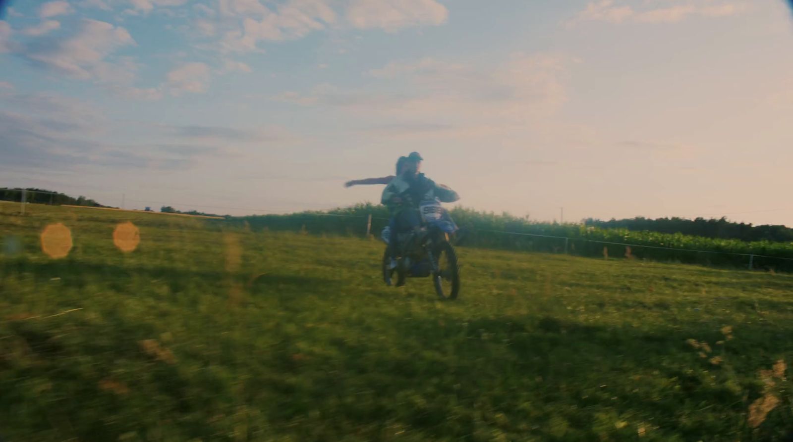 a man riding a motorcycle through a lush green field