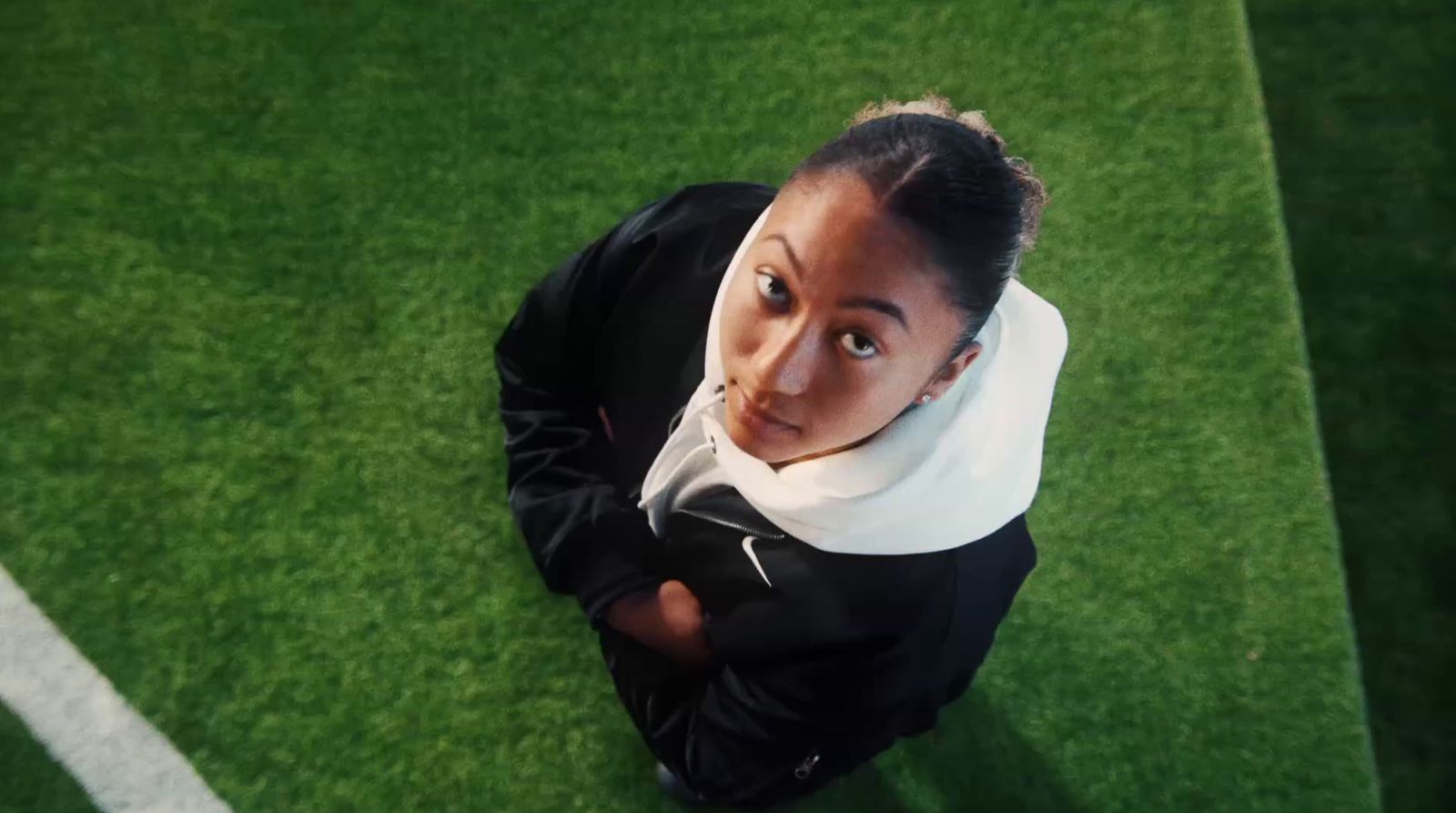 a woman with a scarf around her neck sitting on a soccer field