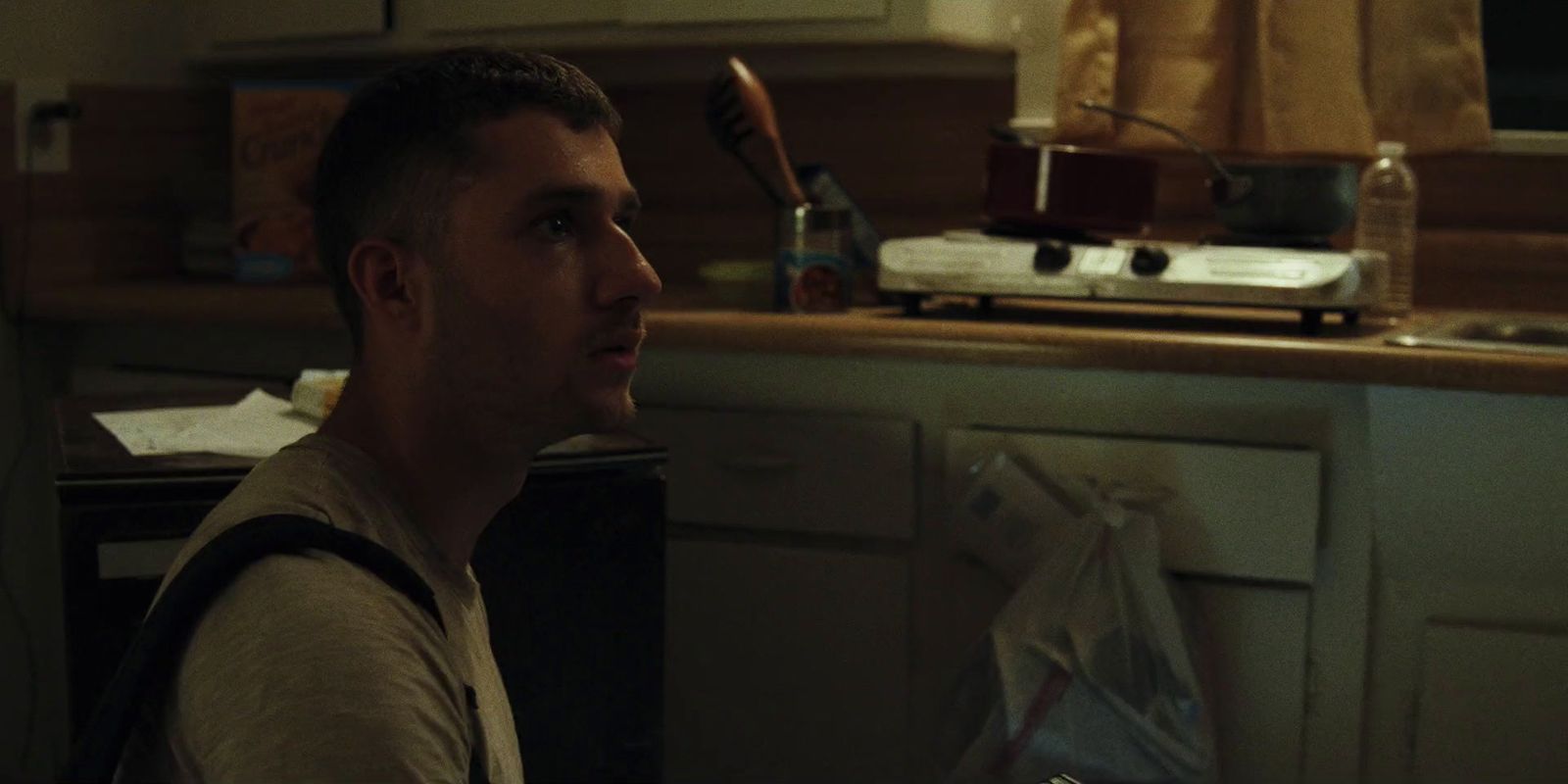 a man sitting in a kitchen next to a counter