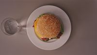 a hamburger on a plate next to a glass of water