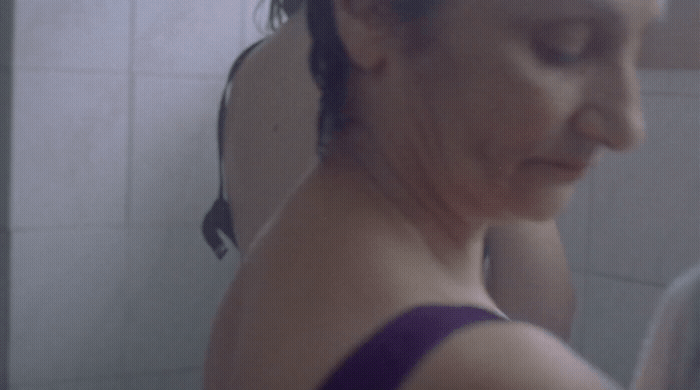 a woman in a purple tank top standing in front of a mirror