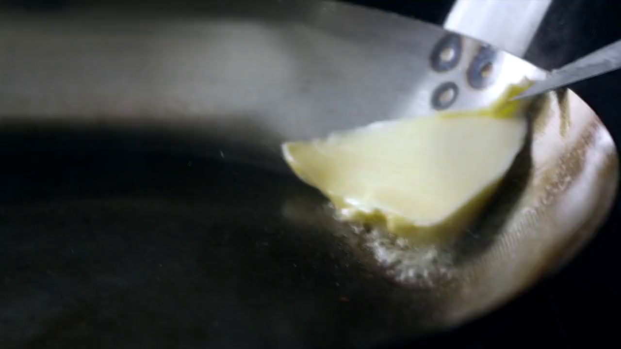 a piece of cheese is being cooked in a frying pan