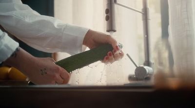 a person holding a cucumber in front of a window