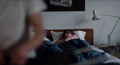 a woman laying in bed with her head on the pillow