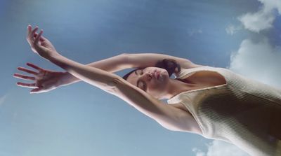 a woman reaching up into the air to catch a frisbee