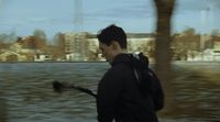 a man walking down a street next to a body of water