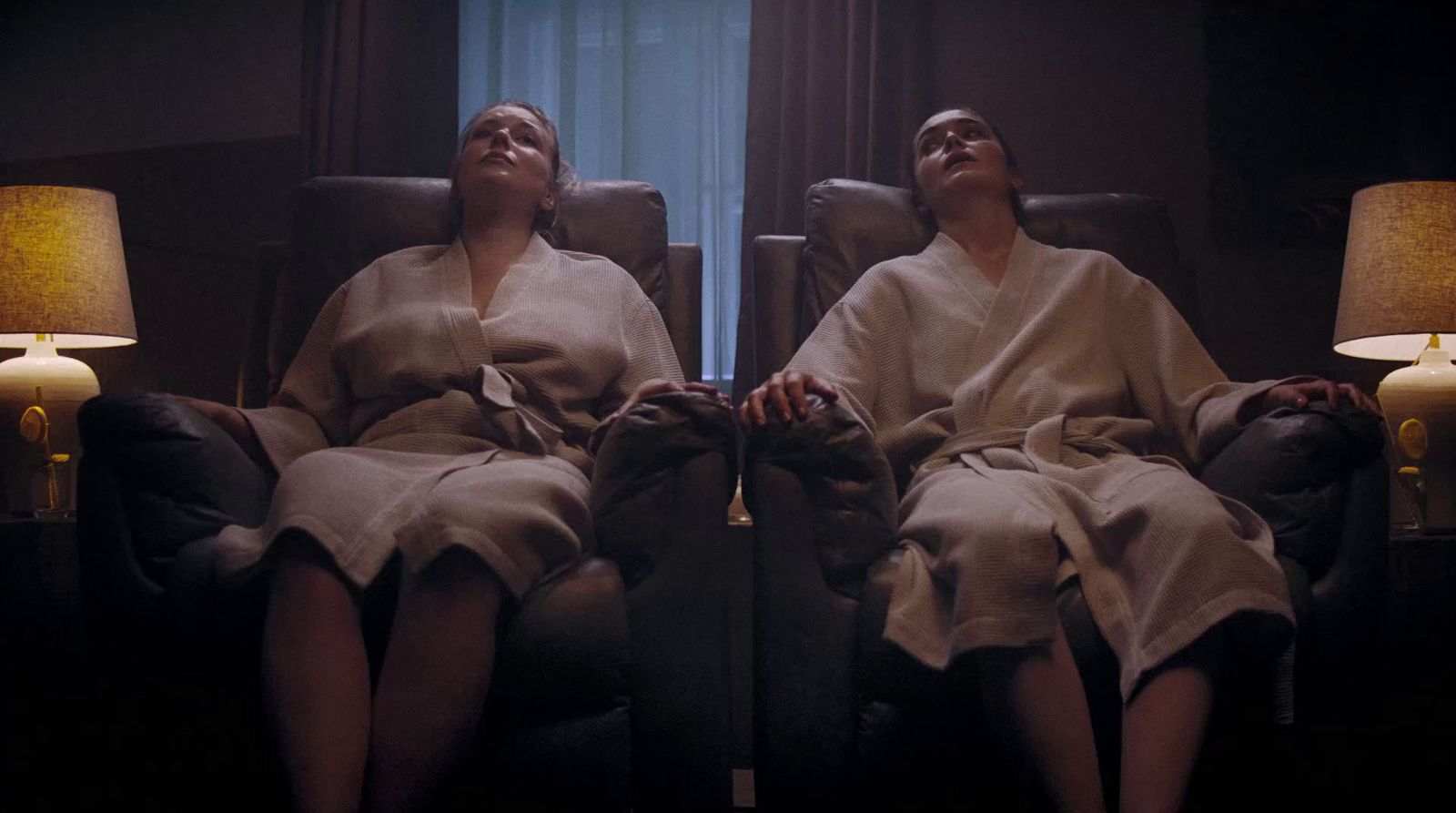 two women in robes sitting in a chair