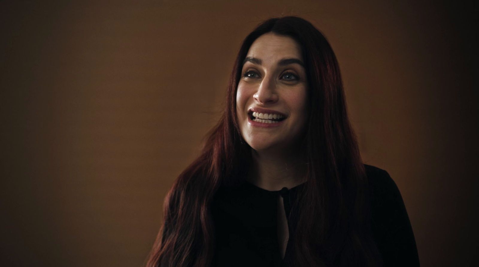 a woman with long red hair smiling at the camera