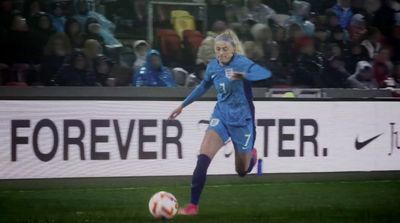 a woman kicking a soccer ball on a field