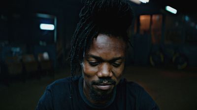 a man with dreadlocks looking down at his cell phone