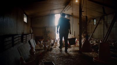 a man standing in a barn next to chickens