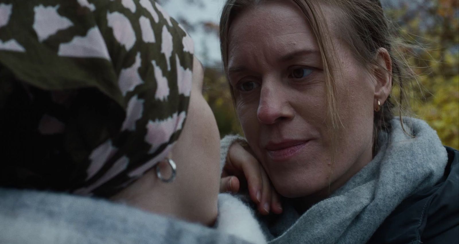 a woman is talking to another woman in a scarf