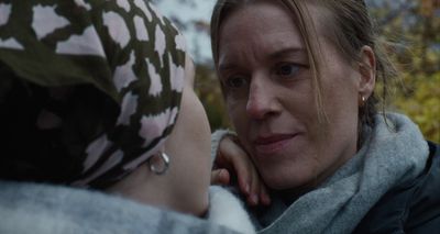 a woman is talking to another woman in a scarf