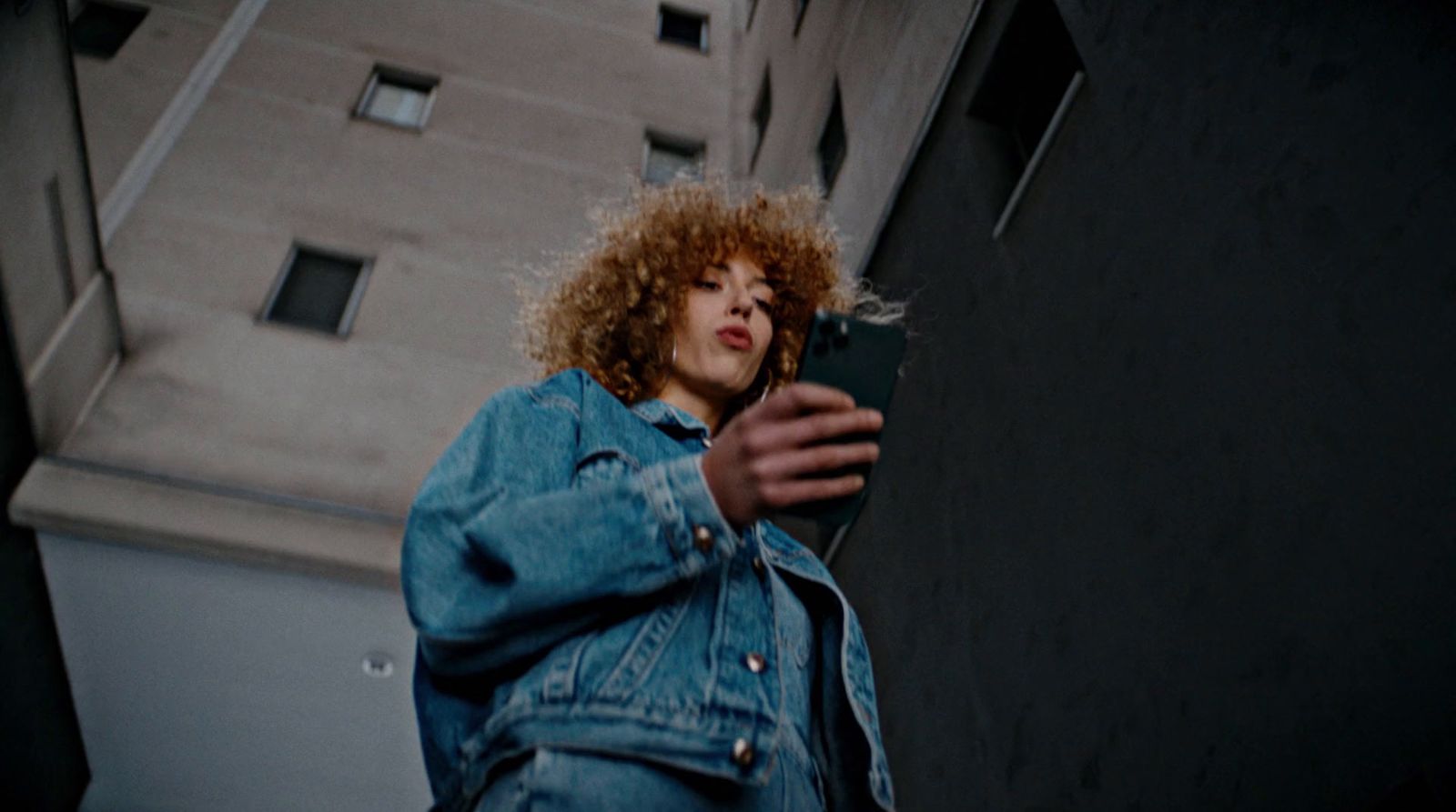 a woman with curly hair is looking at her cell phone