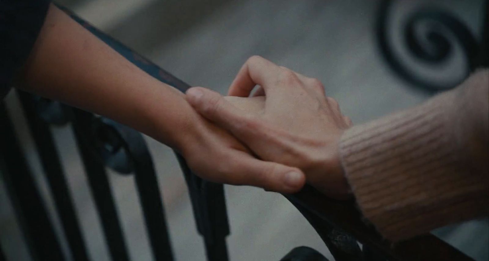 two people holding hands on a railing