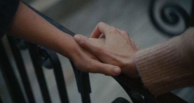 two people holding hands on a railing