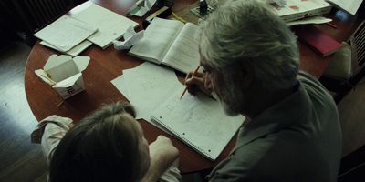 a man and a woman sitting at a table writing