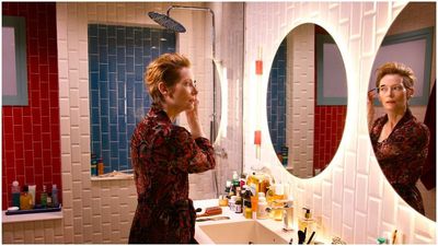 a woman standing in front of a bathroom mirror