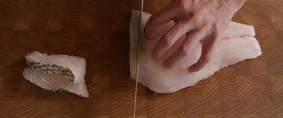 a person is cutting a piece of meat on a cutting board