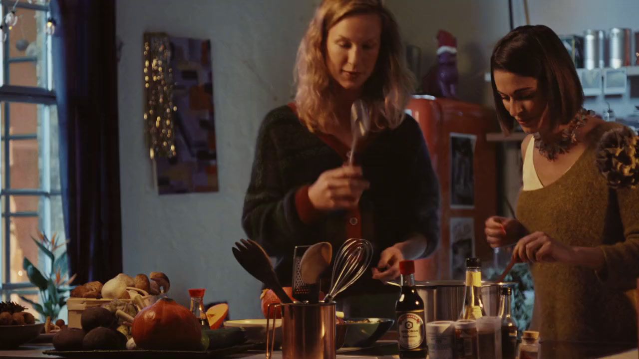 two women standing in a kitchen preparing food