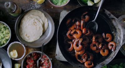 a skillet filled with shrimp next to other dishes of food