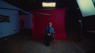 a man sitting in a chair in front of a red screen