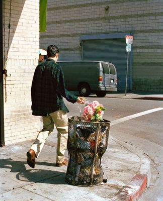 a man walking past a trash can on the side of a road