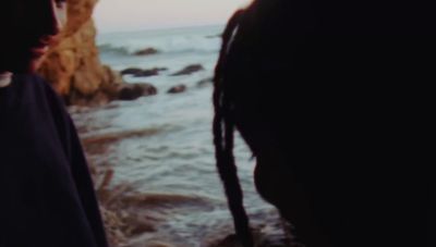 a couple of people standing next to each other near the ocean