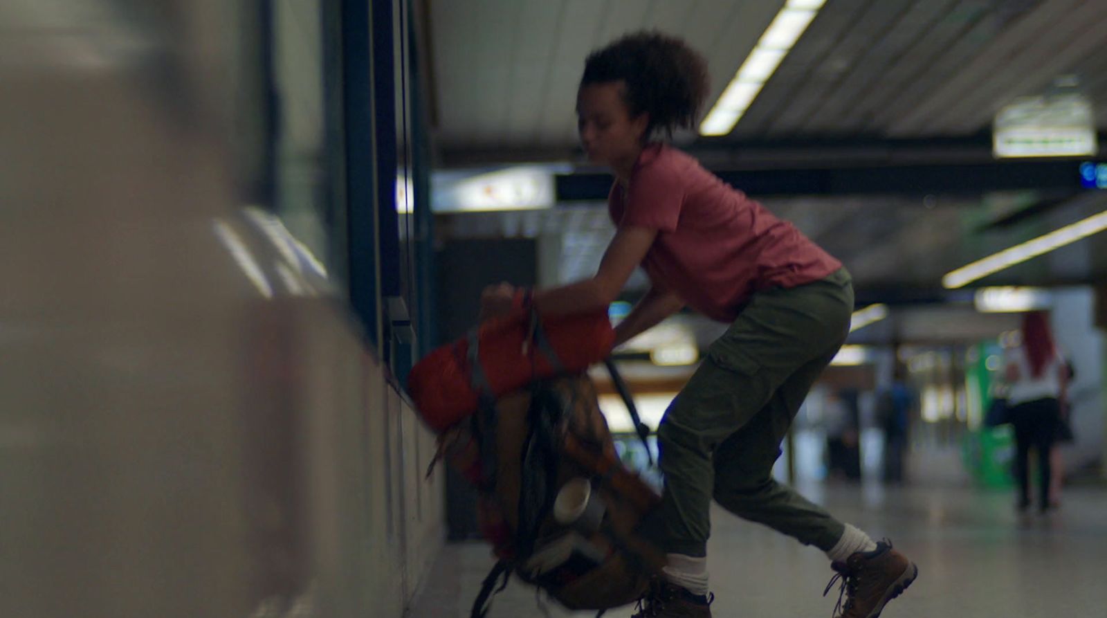 a young girl pushing a luggage cart through an airport