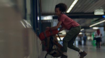 a young girl pushing a luggage cart through an airport