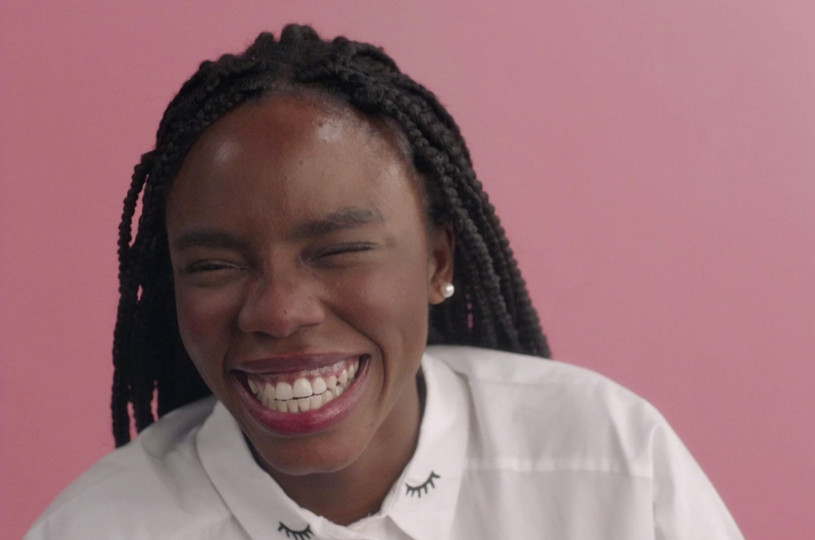 a woman with braids smiling and wearing a white shirt