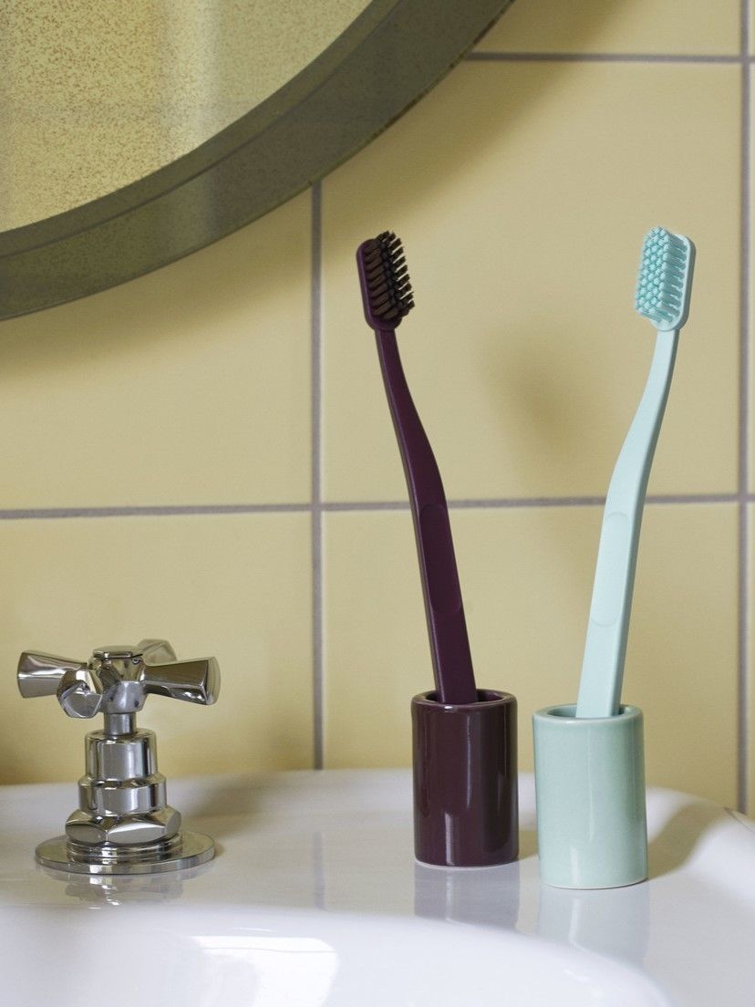 two toothbrushes in a cup sitting on a sink