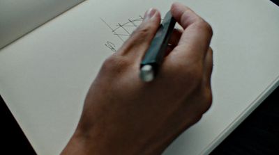 a person writing on a piece of paper with a pen