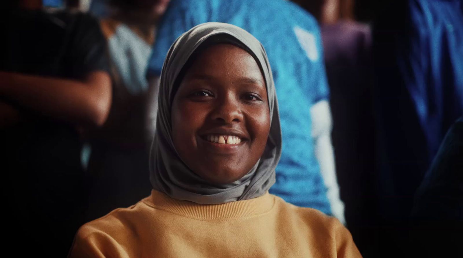 a woman in a headscarf smiles at the camera