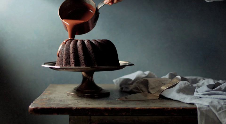 a chocolate cake being drizzled with chocolate sauce