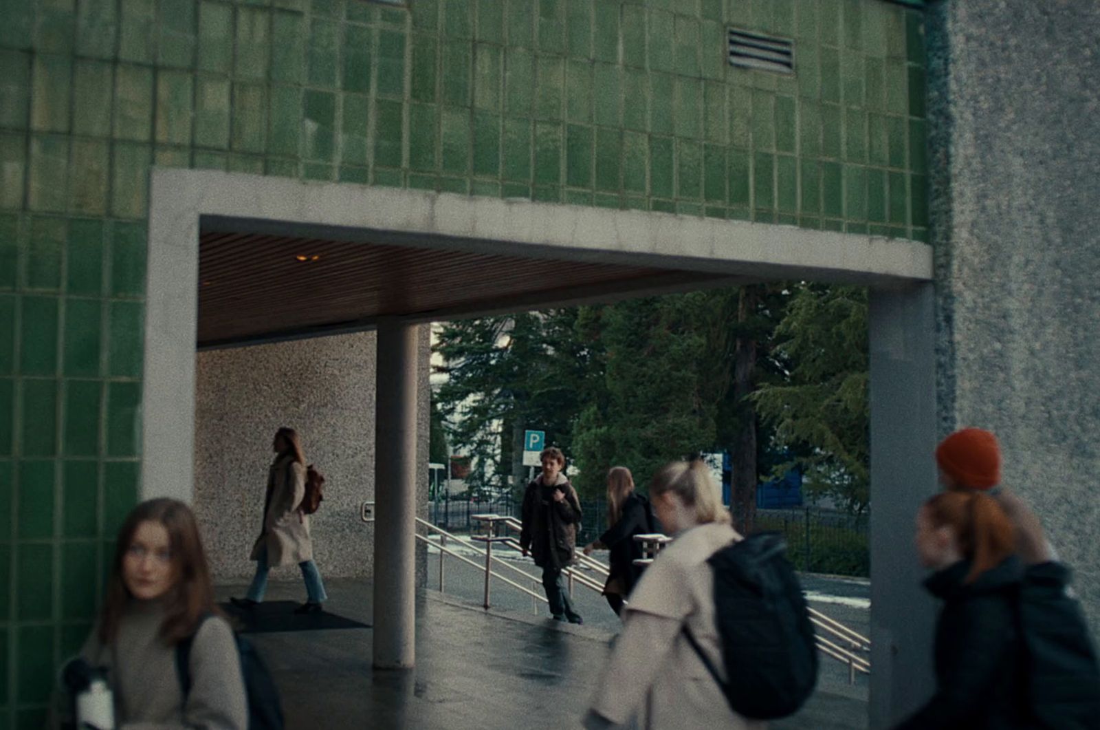 a group of people walking down a sidewalk next to a building