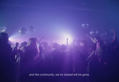 a group of people standing in front of a purple light