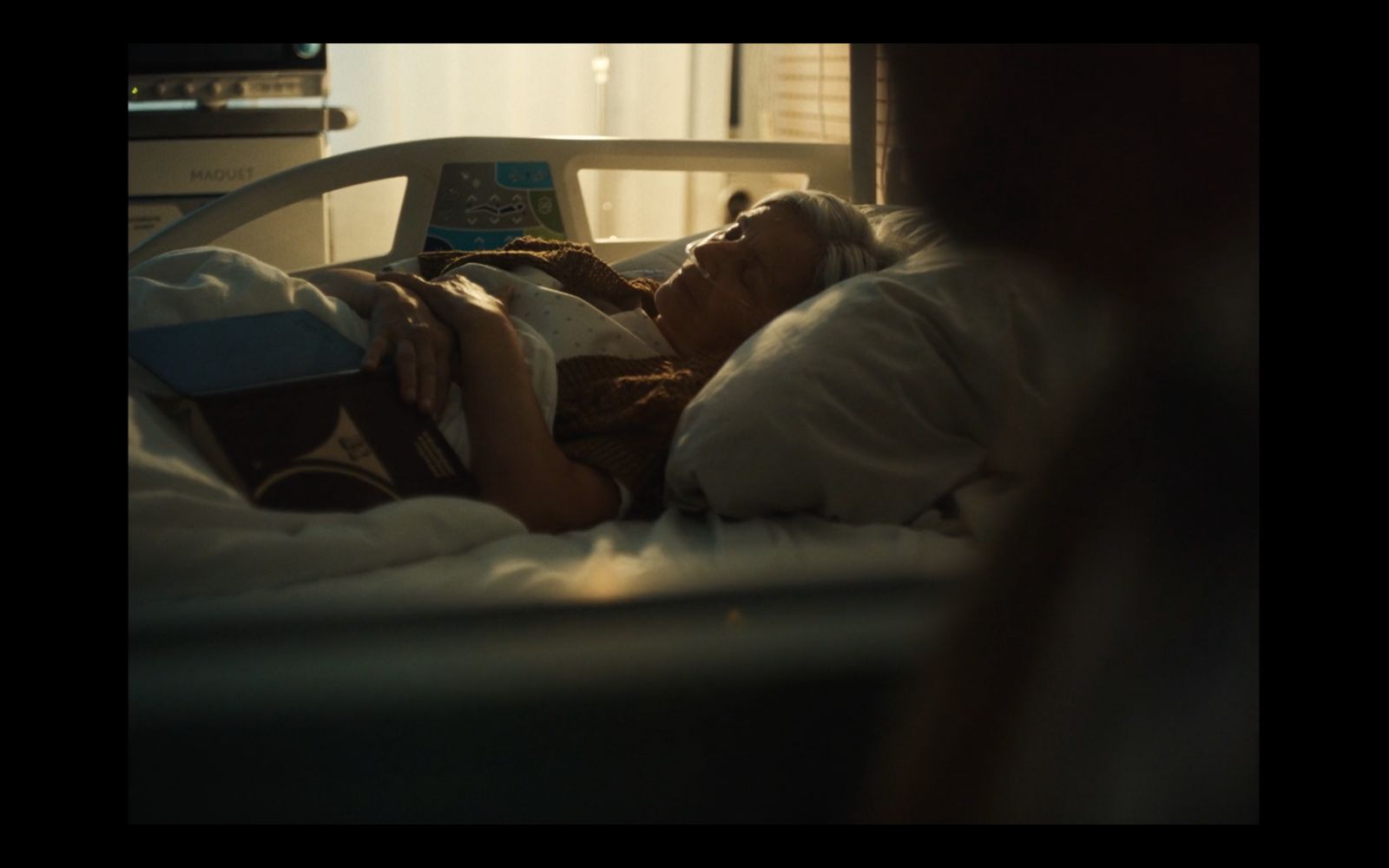 a woman laying in a hospital bed reading a book