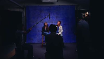 a man and a woman sitting in front of a blue backdrop