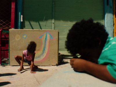 a little girl sitting on the ground in front of a building