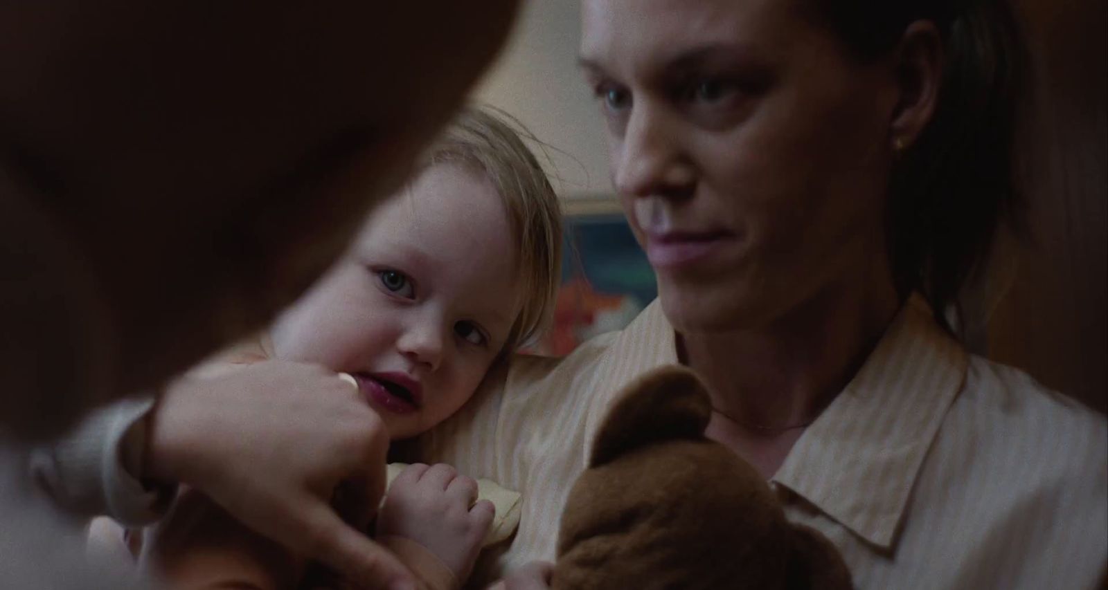 a woman holding a little girl who is holding a teddy bear