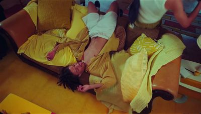 a woman laying on top of a couch covered in yellow blankets