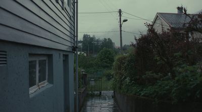 a rain soaked street next to a house