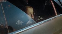 a little girl sitting in a car looking out the window