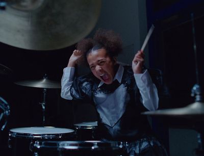 a man with his hands in the air while playing drums