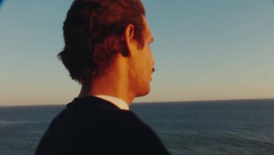 a man in a suit looking out at the ocean